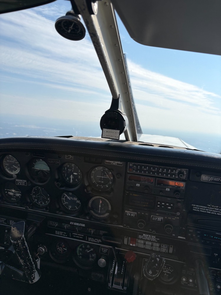 Instrument panel of a small airplane with classic six-pack gauges and radios, seen in flight